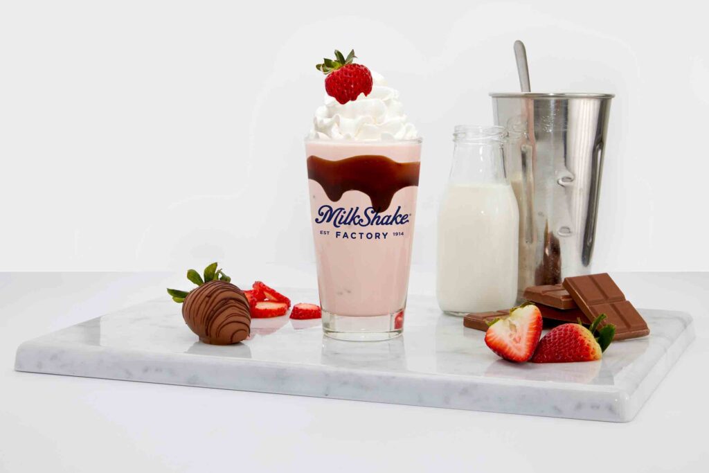 Milkshake with visible ingredients displayed, including fresh fruits, ice cream, and toppings.