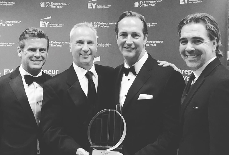 Men in suits carrying a trophy and smiling.