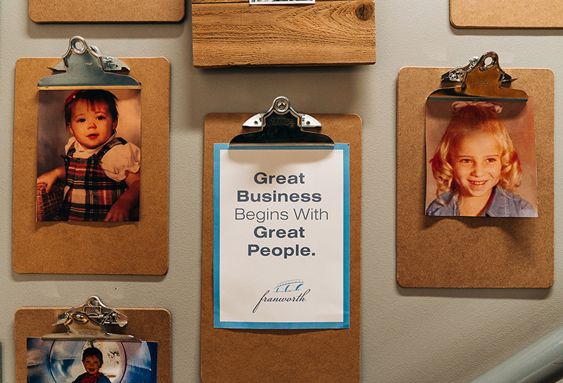 Clipboards on a wall with pictures hanging from them.