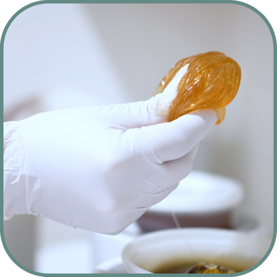 Close-up of a person holding a ball of sugar wax, ready for use in a hair removal treatment at a sugaring franchise.