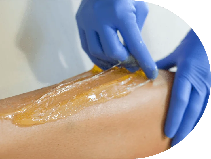 A close-up of sugar wax being applied during a professional hair removal session at a sugaring franchise.