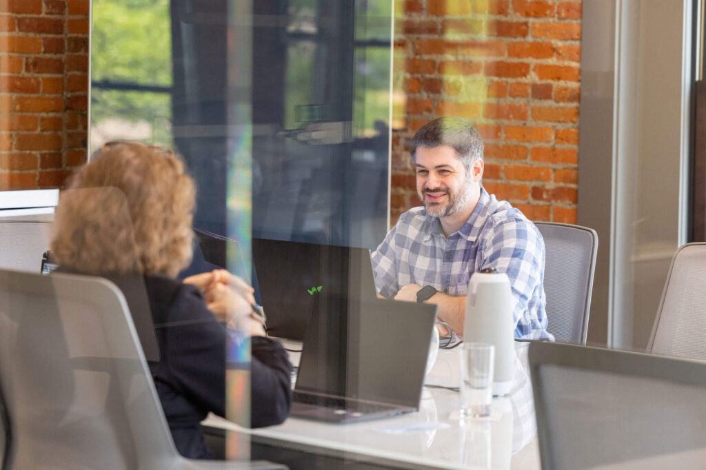 A group of people sitting around a table in a conference room discussing franchisors and franchisees.