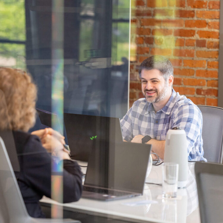 A group of people sitting around a table in a conference room discussing franchisors and franchisees.