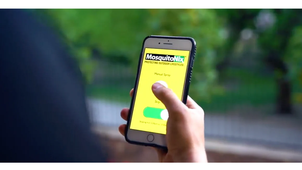 Person using MosquitoNix mobile app to control a mosquito misting system.