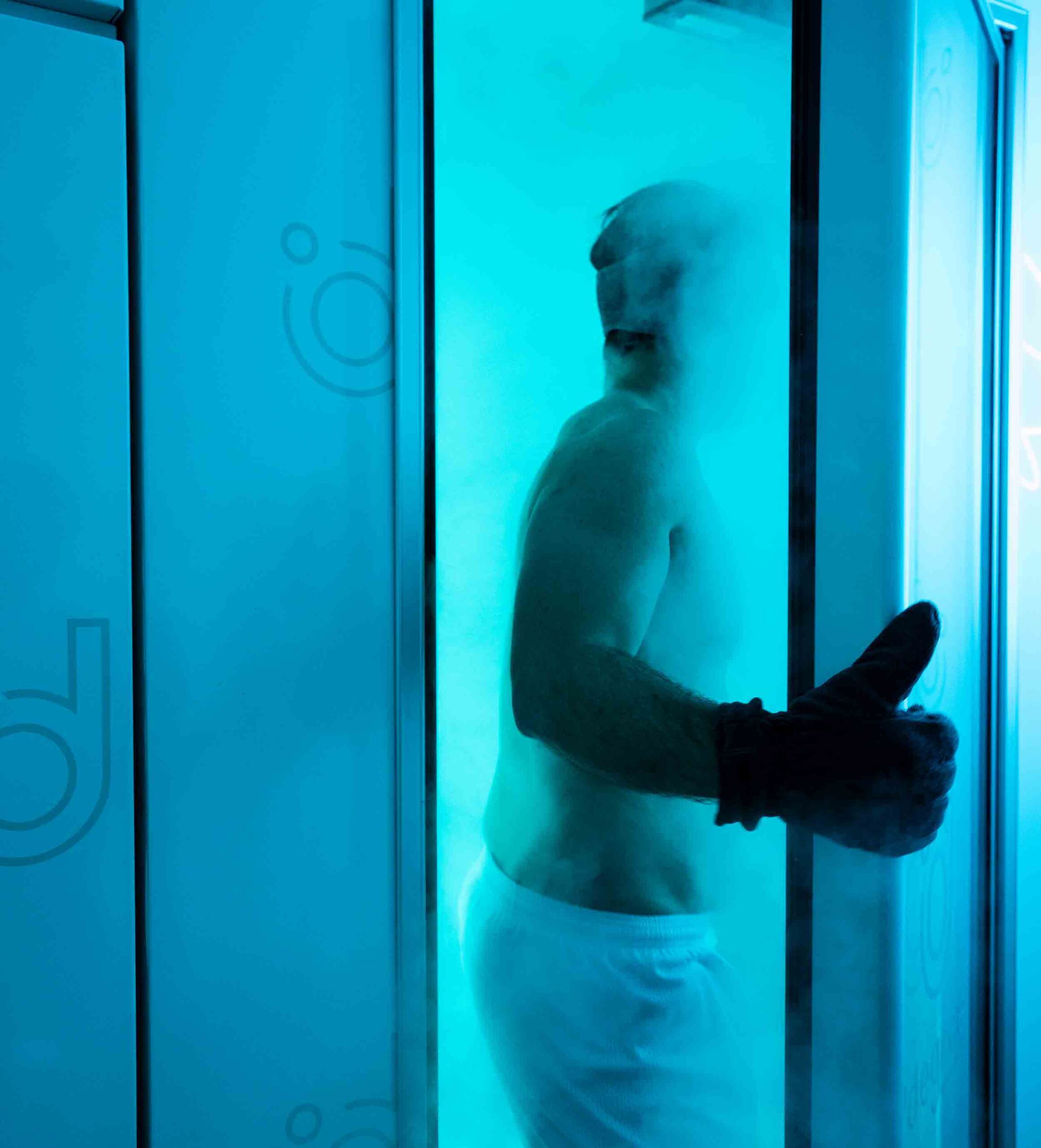 An individual standing in a cryotherapy chamber receiving cold therapy as part of a wellness franchise’s service offerings.