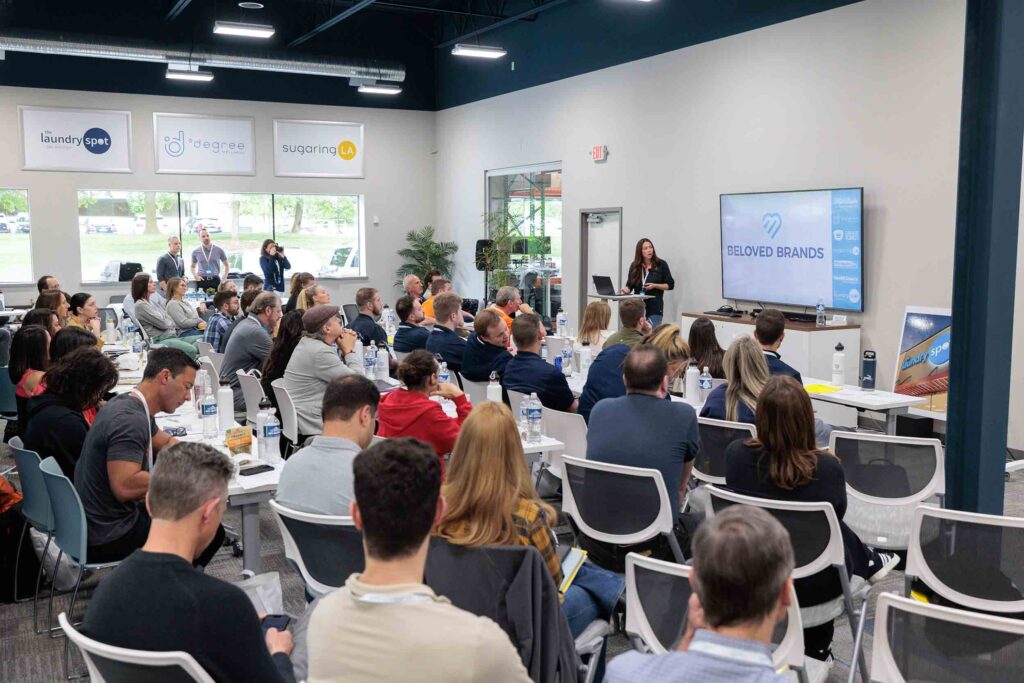 A large group of people attentively listening to a presentation about buying a franchise. 